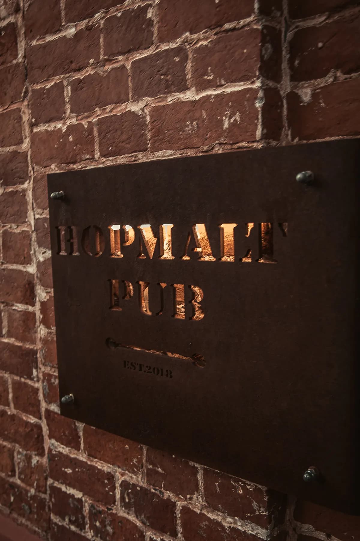 Вывеска HOPMALT Pub на кирпичной стене